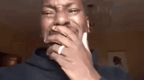 A Man With A Ring On His Finger Is Covering His Mouth With His Hands . GIF