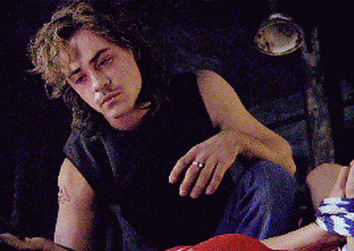 A Man With A Ring On His Finger Is Sitting On The Floor Looking At The Camera . GIF