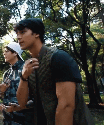 A Man With A Ring On His Finger Stands Next To Another Man In A Plaid Shirt GIF