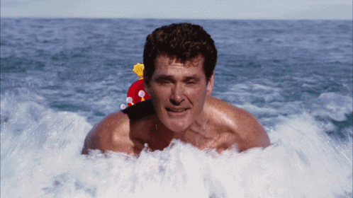 A Man With A Santa Hat On His Head Is Swimming In The Ocean GIF