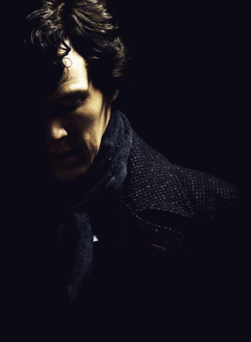 A Man With A Scarf Around His Neck Looks Down GIF