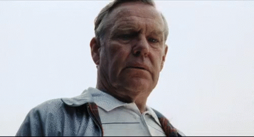 A Man With A Serious Look On His Face Is Wearing A Plaid Shirt GIF