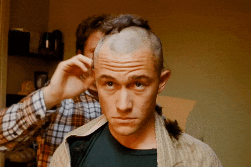 A Man With A Shaved Head Is Getting His Hair Cut By Another Man GIF
