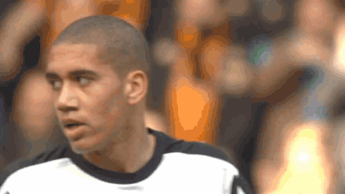 a man with a shaved head is wearing a white shirt
