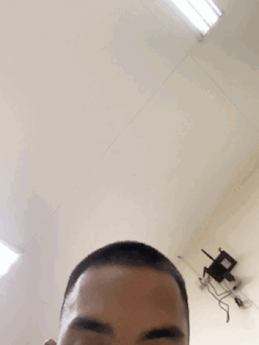 A Man With A Shaved Head Looks At The Camera With A Chair In The Background GIF