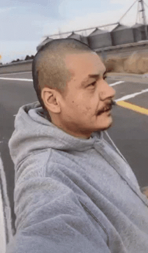 A Man With A Shaved Head Wearing A Grey Sweatshirt GIF