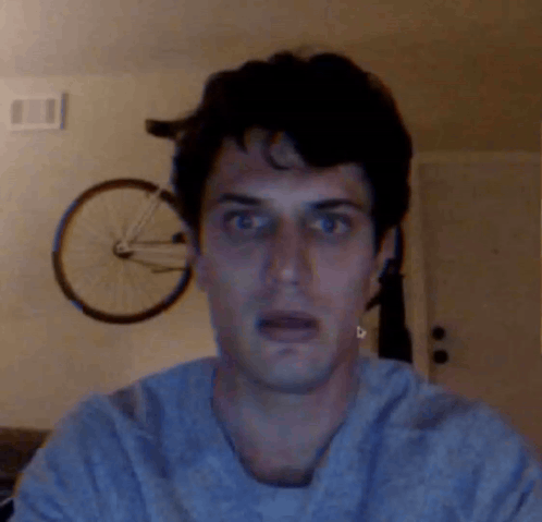 A Man With A Shocked Look On His Face Stands In Front Of A Bicycle GIF