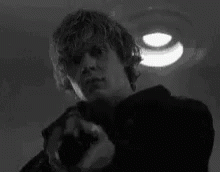 A Man With A Skull Painted On His Face Is Pointing A Gun . GIF