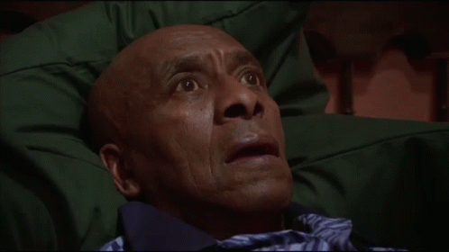 a man with a surprised look on his face is laying on a green blanket