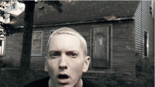A Man With A Surprised Look On His Face Stands In Front Of A House That Says 1990 On The Door GIF