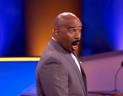 A Man With A Surprised Look On His Face Stands In Front Of A Microphone GIF
