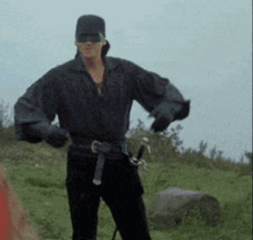 A Man With A Sword In His Belt Is Standing In A Field GIF