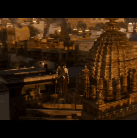 A Man With A Sword On His Back Stands In Front Of A Building GIF