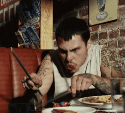 A Man With A Tattoo On His Arm Is Eating A Pizza GIF