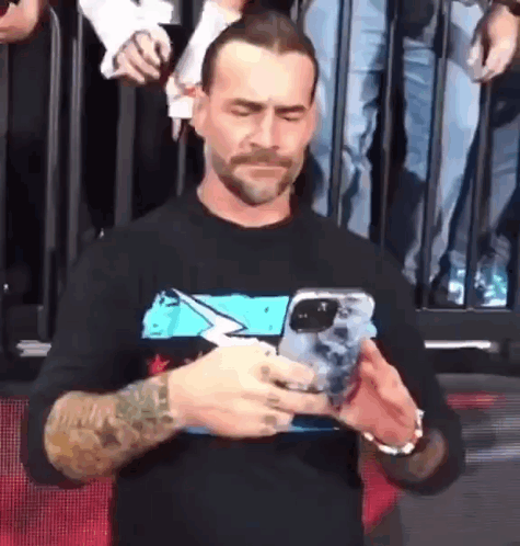 A Man With A Tattoo On His Arm Is Holding A Cell Phone . GIF