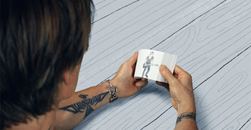 A Man With A Tattoo On His Arm Is Holding A Drawing Of A Man Playing A Guitar GIF