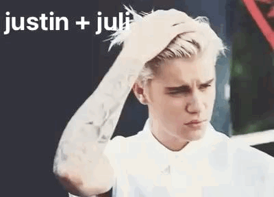 A Man With A Tattoo On His Arm Is Holding His Hair . GIF