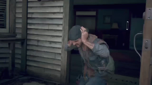 A Man With A Tattoo On His Arm Is Squatting On A Wooden Deck GIF