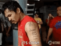 A Man With A Tattoo On His Arm Is Standing In A Gym And Says `` It 'S Ova '' . GIF