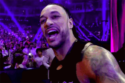 A Man With A Tattoo On His Arm Is Standing In Front Of A Crowd And Smiling . GIF
