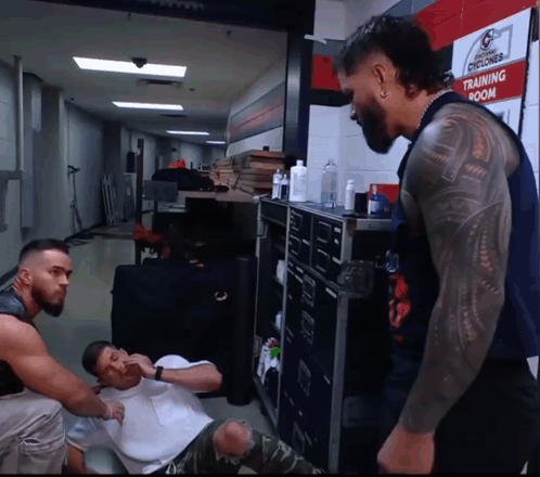 a man with a tattoo on his arm is standing in front of a sign that says training room