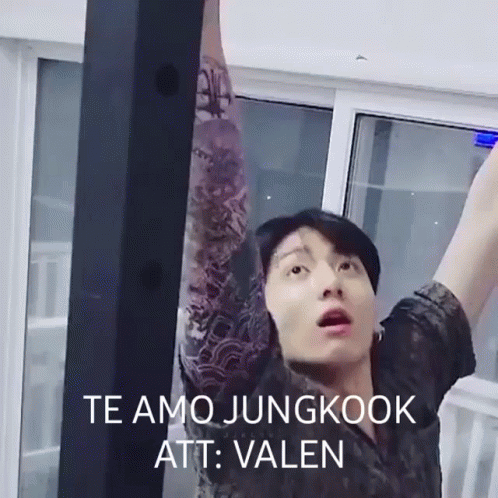 A Man With A Tattoo On His Arm Is Standing In Front Of A Window With His Arms Outstretched . GIF