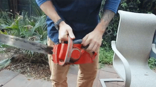 A Man With A Tattoo On His Arm Is Using A Chainsaw GIF