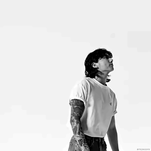 A Man With A Tattoo On His Arm Is Wearing A White T-Shirt With The Letter K On It GIF