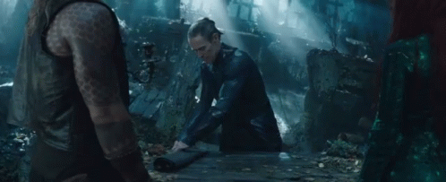 A Man With A Tattoo On His Arm Sits On A Wooden Table In A Dark Forest GIF