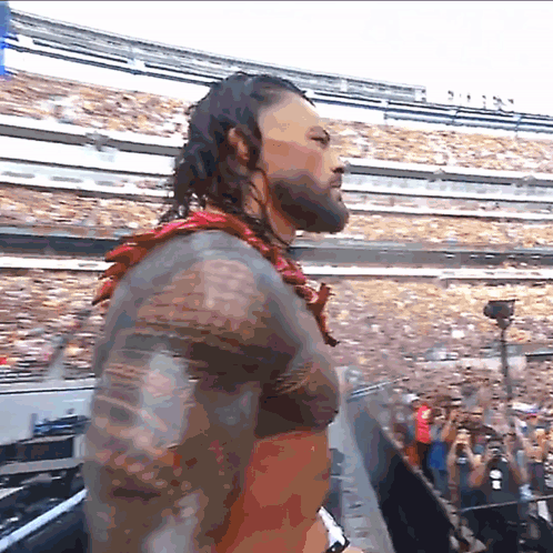 A Man With A Tattoo On His Arm Stands In Front Of A Crowd GIF