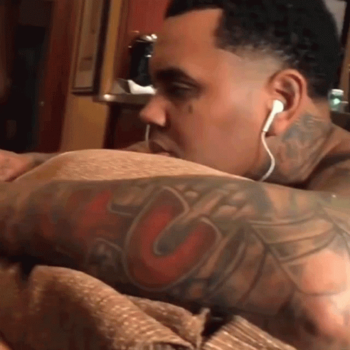 A Man With A Tattoo On His Arm Wearing Ear Buds GIF