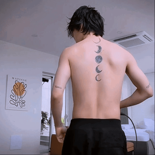 A Man With A Tattoo On His Back Is Standing In Front Of A Framed Matisse Painting GIF