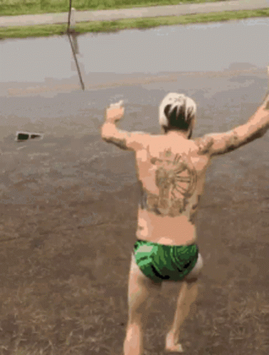 A Man With A Tattoo On His Back Jumping Into A Body Of Water GIF