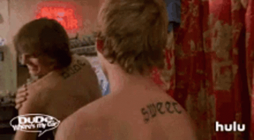 A Man With A Tattoo On His Back Looks At Himself In A Mirror . GIF