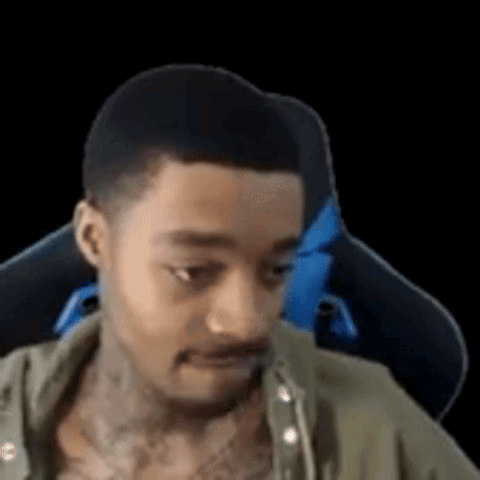 A Man With A Tattoo On His Chest Is Sitting In A Gaming Chair And Looking At The Camera . GIF