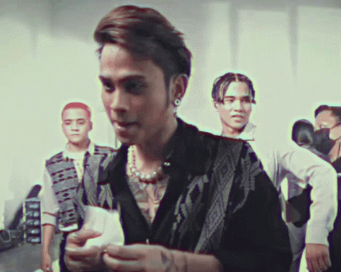 A Man With A Tattoo On His Chest Is Standing In A Crowd GIF