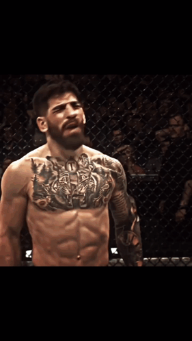 A Man With A Tattoo On His Chest Is Standing In Front Of A Sign That Says Pro.com GIF