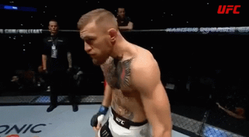 A Man With A Tattoo On His Chest Stands In A Boxing Ring With Ufc Written On The Bottom GIF