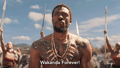 A Man With A Tattoo On His Chest Stands In Front Of A Group Of People Holding Spears And Says " Wakanda Forever " GIF