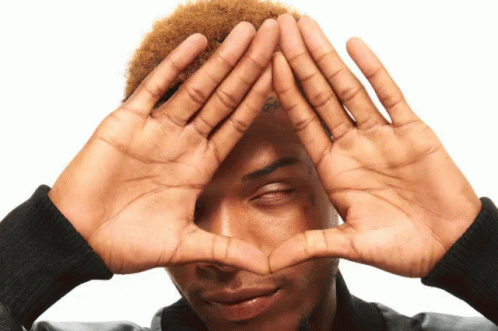A Man With A Tattoo On His Forehead Makes A Heart With His Hands GIF