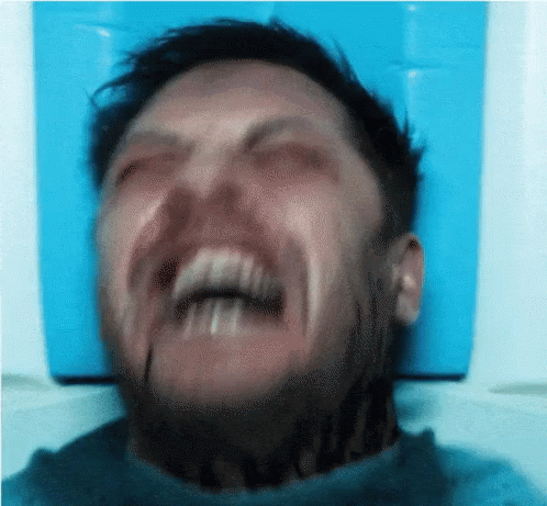A Man With A Tattoo On His Neck Is Making A Funny Face With His Mouth Open . GIF