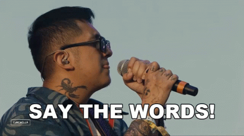 A Man With A Tattoo On His Neck Is Singing Into A Microphone With The Words Say The Words Behind Him GIF