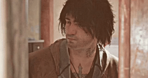 A Man With A Tattoo On His Neck Is Standing In A Room . GIF