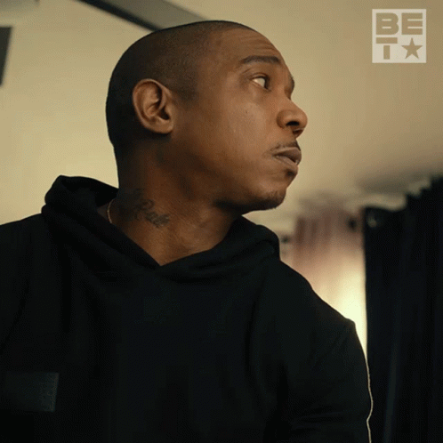 A Man With A Tattoo On His Neck Looks To The Side With A Be T Logo Behind Him GIF