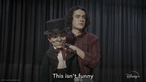 A Man With A Top Hat Is Standing Next To A Puppet That Says This Isn 'T Funny GIF