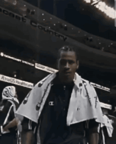A Man With A Towel Around His Neck Is Standing In Front Of A Sign That Says " Peace Country " GIF
