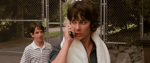 A Man With A Towel Around His Neck Is Talking On His Cell Phone GIF