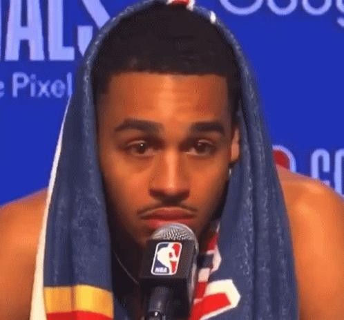 A Man With A Towel Wrapped Around His Head Talking Into A Microphone . GIF