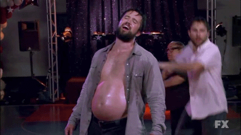 A Man With A Very Large Belly Is Dancing On A Stage In Front Of A Fx Logo . GIF