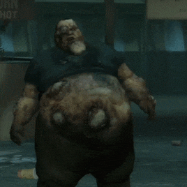 A Man With A Very Large Belly Is Standing In Front Of A Sign That Says Hot GIF